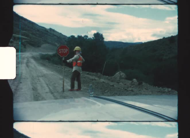 The man holds a stop sign on the dirt road