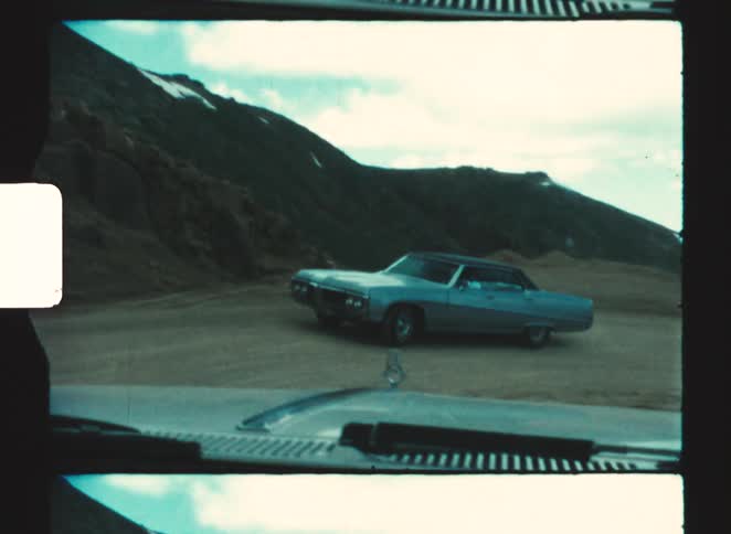 pikes peak colorado springs Filmed from the perspective of a moving car a lightblue vintage sedan is seen stopped on a dirt road up next to a steep rocky hillside