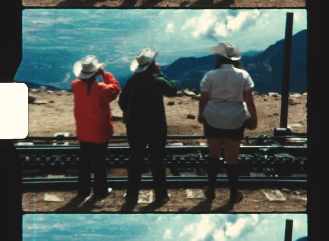 pikes peak colorado springs 1970  Three people standing near train tracks overlooking a mountainous view