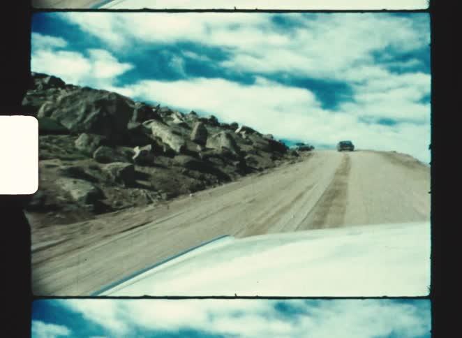 pikes peak colorado springs 1970  Vehicles travel on a dirt road passing a boulder strewn slope on a cloudy day