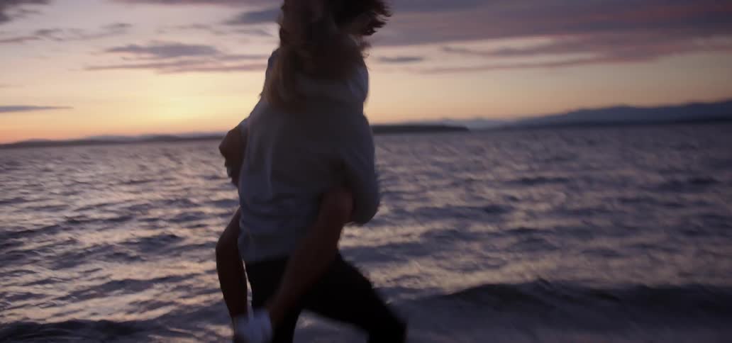 A man carries a woman into ocean water and threatens to drop her