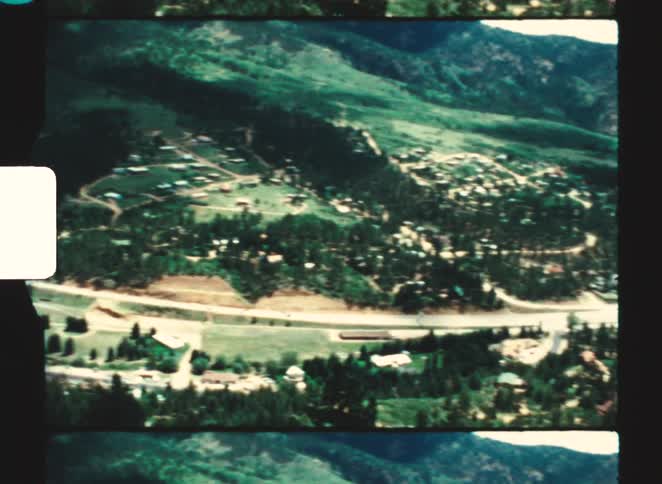 Aerial view of an urban area in a mountainous valley with a main road cutting through the landscape