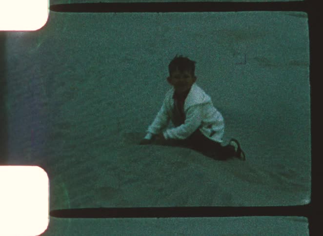The boy is digging in the sand with his hands