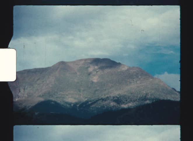 Rocky mountain stands out under partly cloudy sky captured in vintage film style
