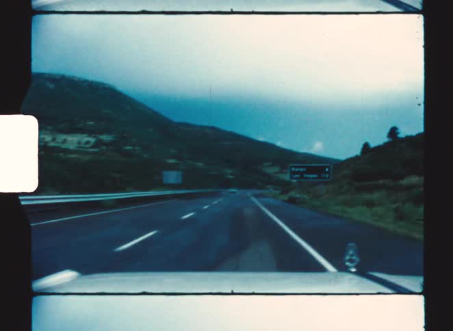Empty highway crossing a mountainous area with road signs at dusk