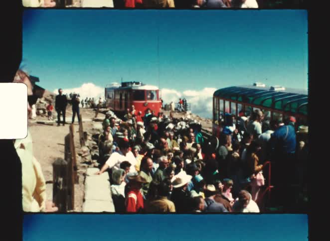 pikes peak colorado springs 1970  A crowd of people wait to board a slow moving train as it reaches a mountain peak