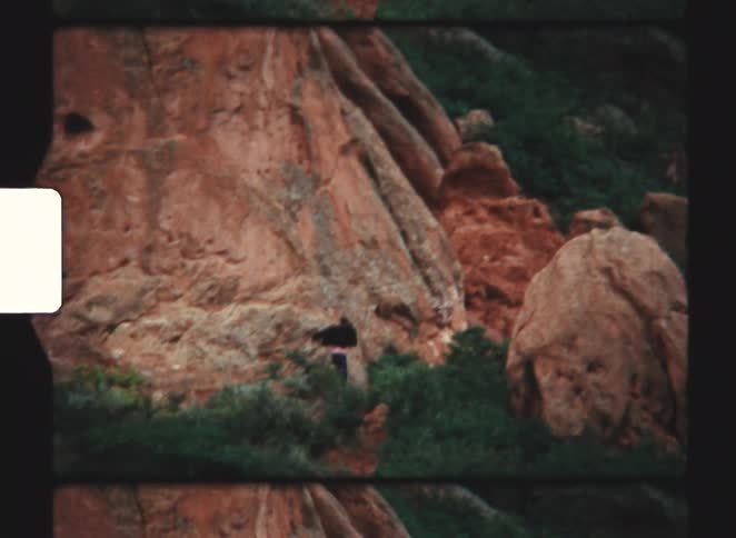 A person running beside a rocky mountain in the wild at midday