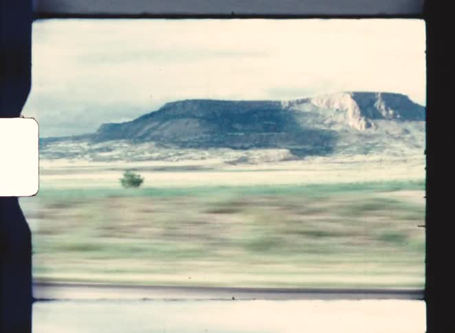 Flattopped mountain dominates arid landscape under partly cloudy sky