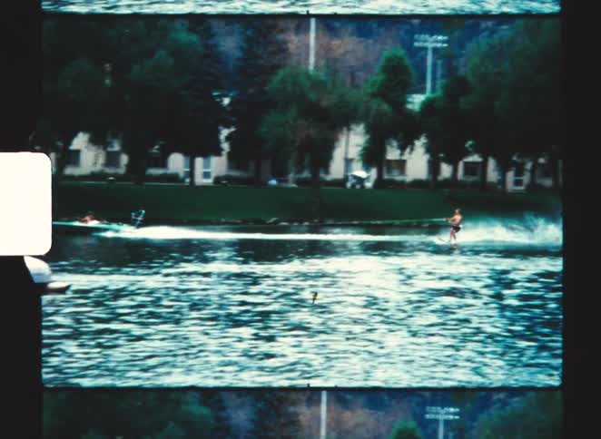 Person slides on a plank while holding onto a rope in a moving boat