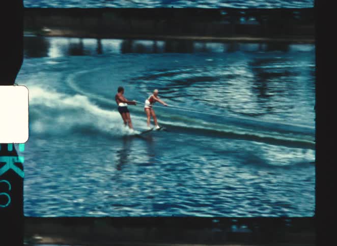 Two people are water skiing side by side