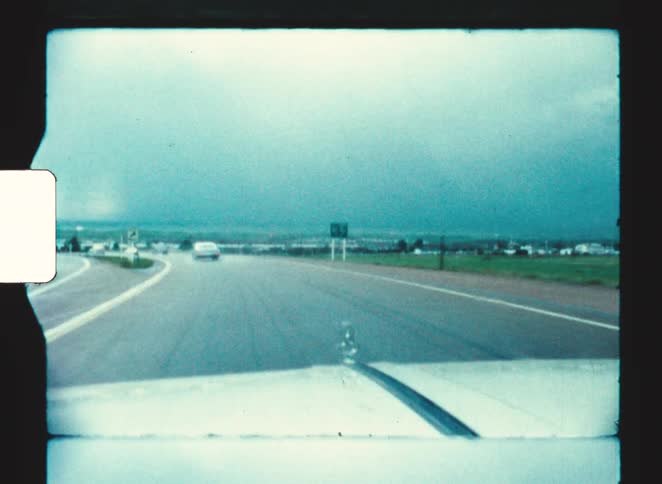The car is driving on the highway past the mountain