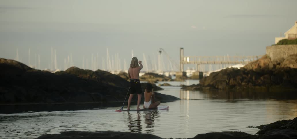 A man and woman ride on a paddle board