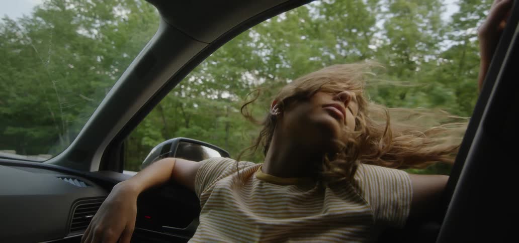 Woman riding in a car leans head out the window