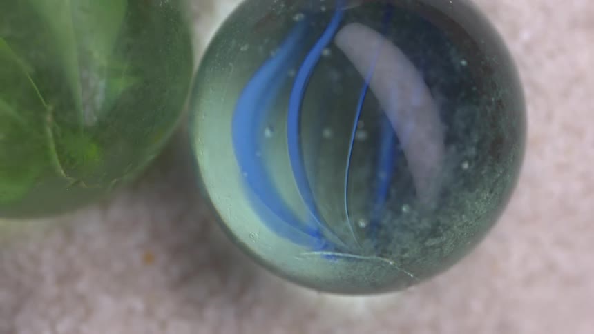 Two large green balls placed side by side one containing green leaves and the other filled with blue feathers