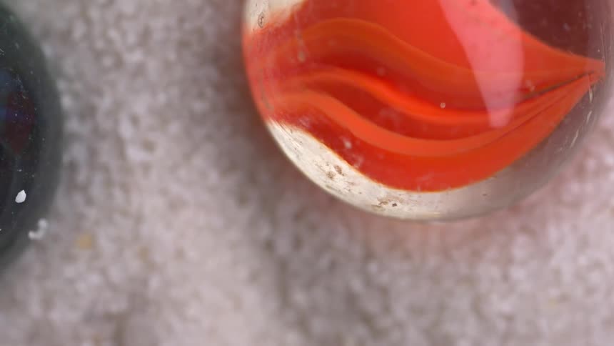 Colored marbles rest on a lightcolored surface with a granular texture