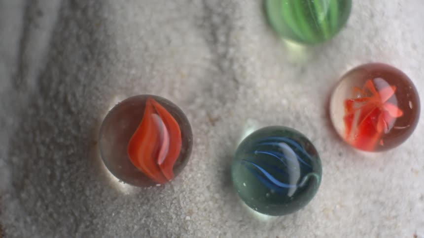 Colorful glass marbles displayed over a shiny white fabric