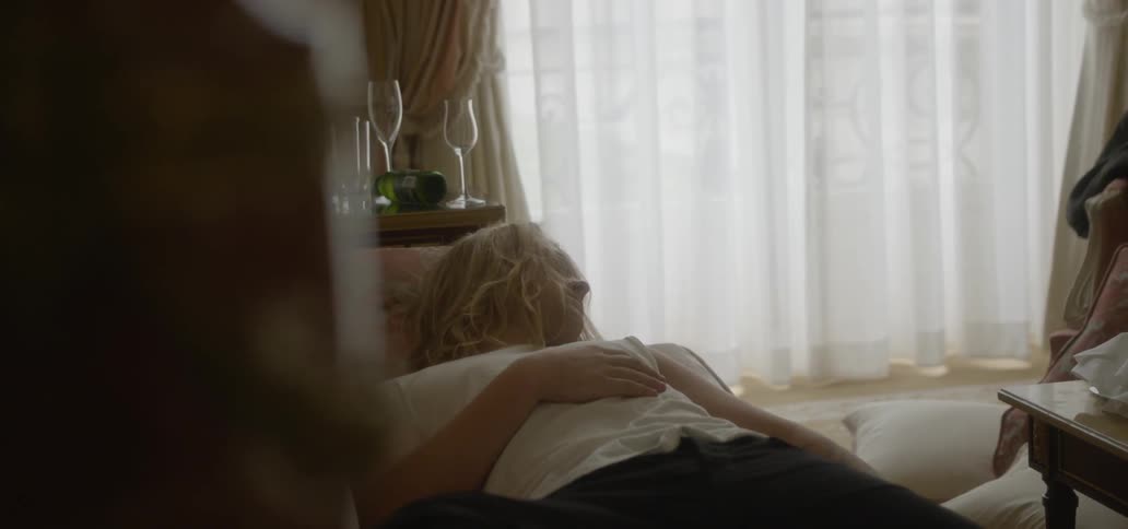 A man in a white shirt sleeps on a couch