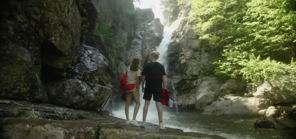 A man and woman watch a waterfall in the wilderness