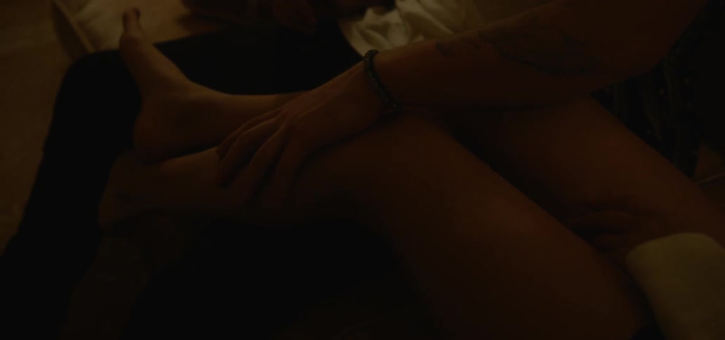 Man rubbing woman's leg in dimly lit room