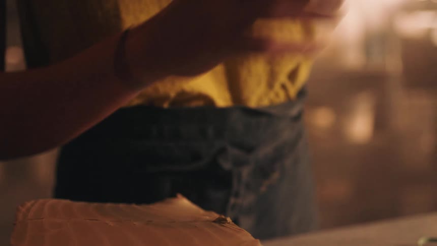 Female hands working on square pieces of soft clay over a table indoors