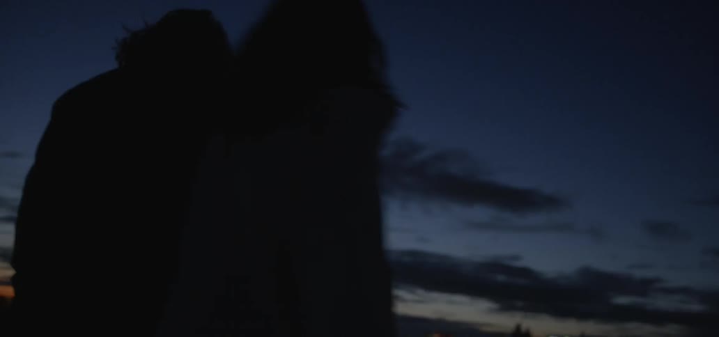 A man and woman walk and spin outside at sunset