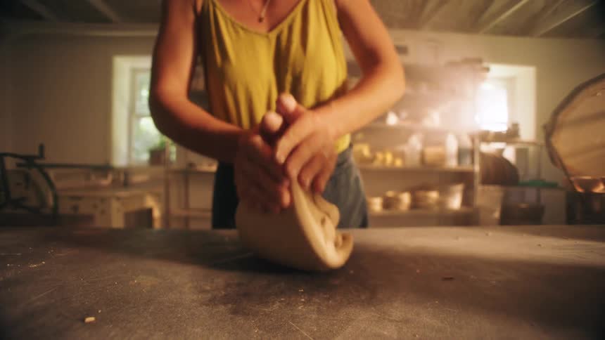 A persons hand using a piece of clay to create a model on a table