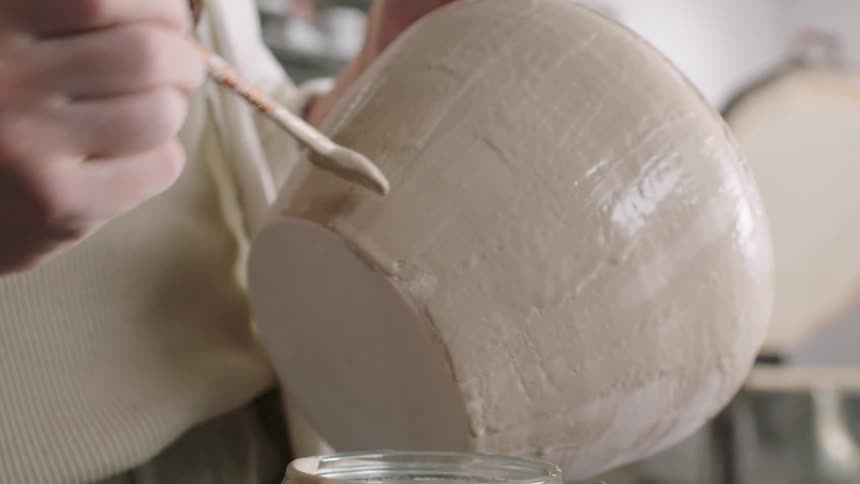 Female hands painting a ceramic bowl using a brush indoors during day time