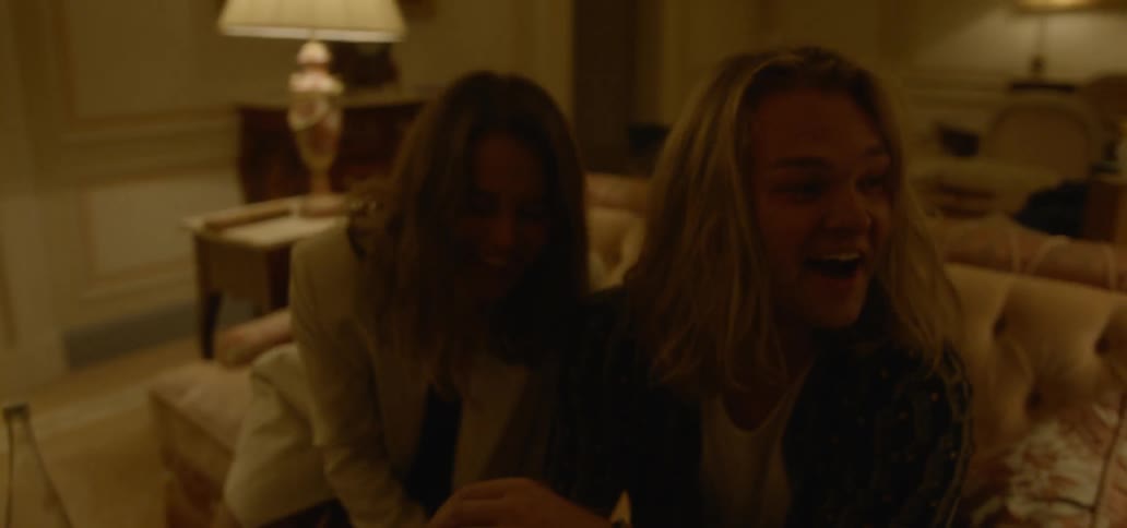 A man and woman sit on a sofa laughing