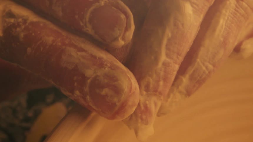 A persons hands gripping the edge of a rapidly rotating ceramic object
