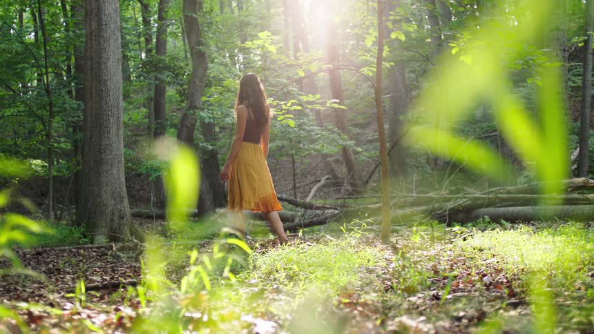 Young woman wearing a long skirt walks into the woods