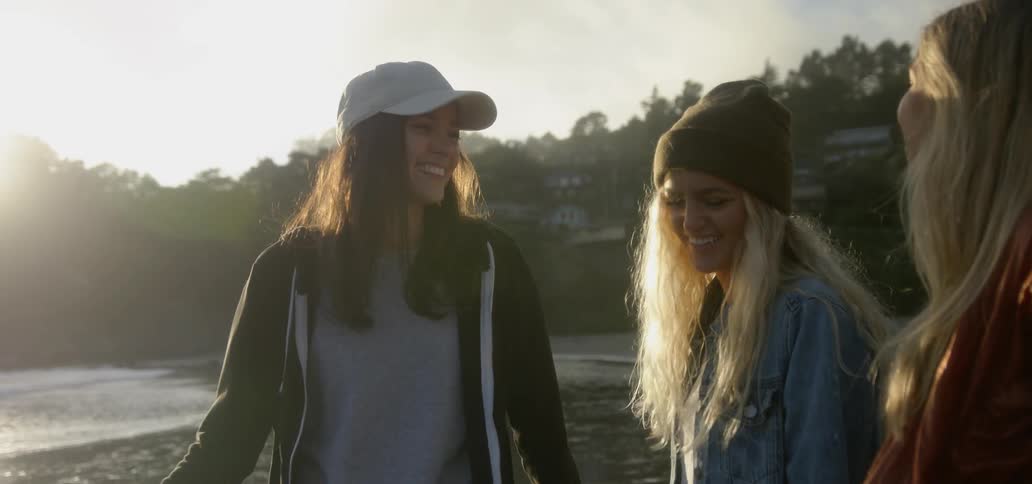 Three women laugh and talk by the water