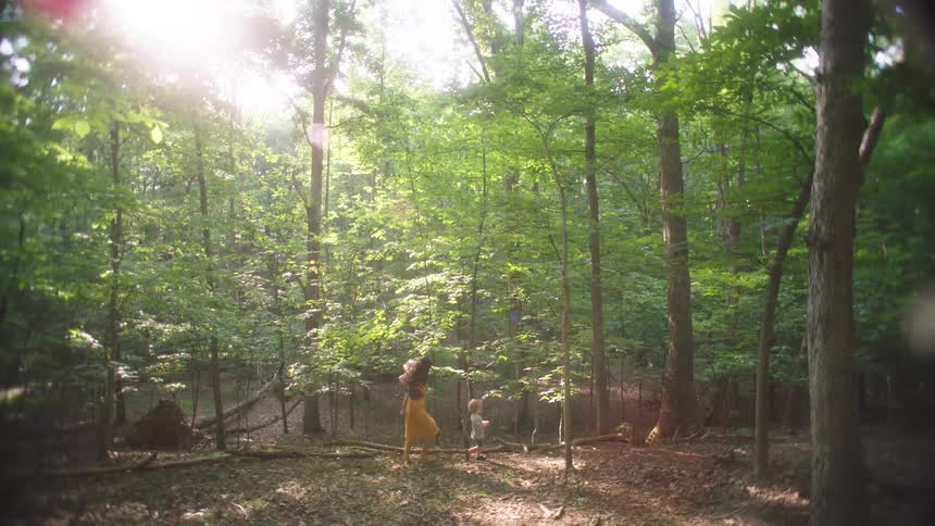 Woman walking through the woods with her young children