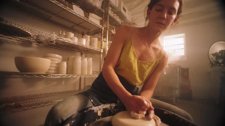 A woman makes a ceramic bowl on a pottery wheel