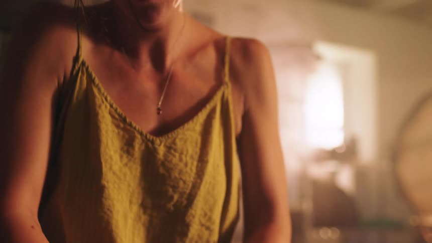 Bathed in the golden glow of a pottery studio a woman rhythmically kneads a lump of raw clay on a workbench her hands firmly pressing and folding the material to prepare it for sculpting