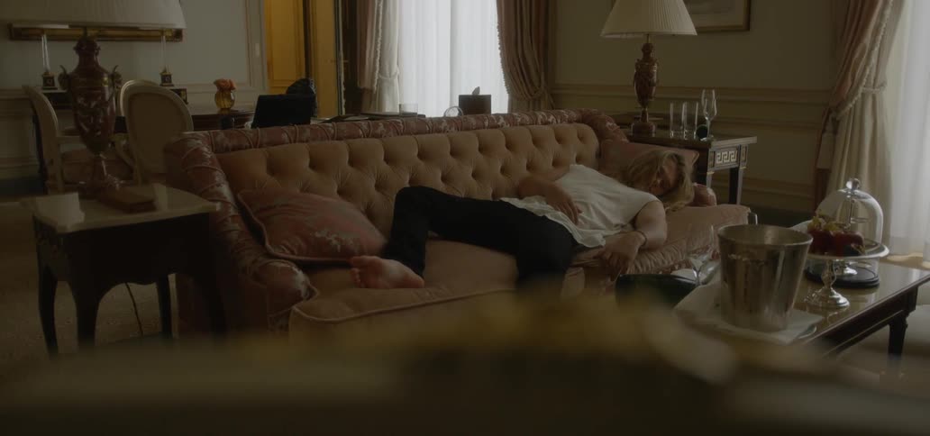 A man naps on a pink couch