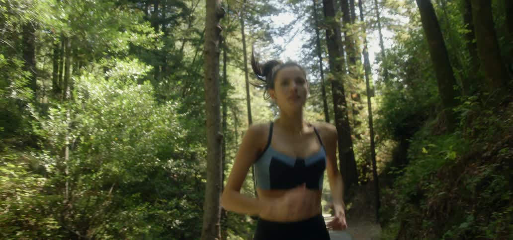 A young woman is jogging in a forested area