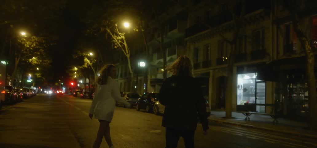 A man and woman cross a city street at night