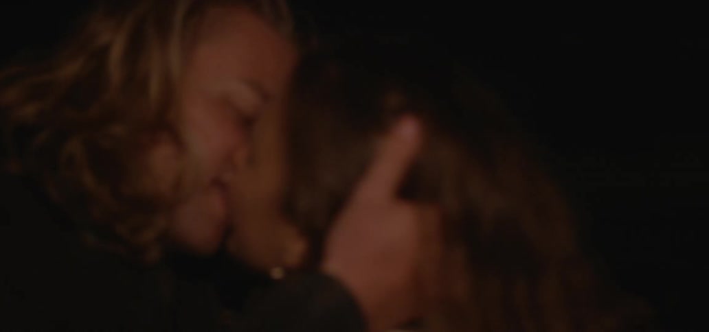 A man and a woman outside at night kissing