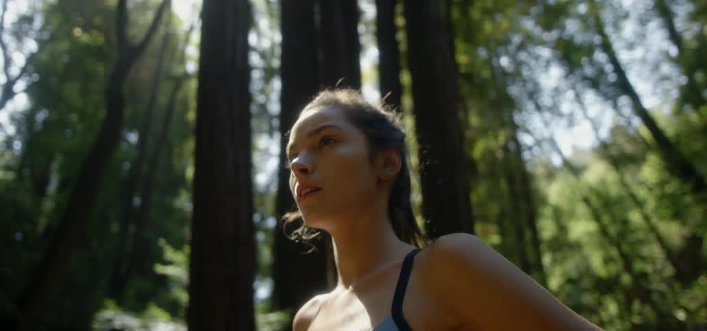 A woman stands with tall trees all around