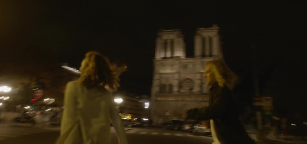 A man and woman run across a city street