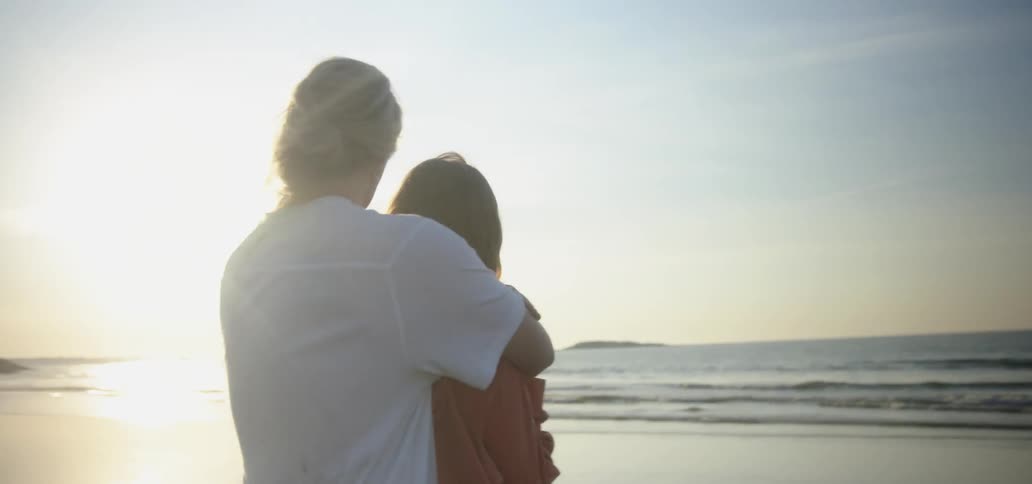 A man embraces a woman on a sandy beach