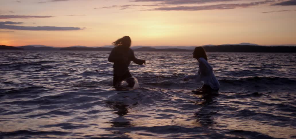 Two girls run up out of the ocean