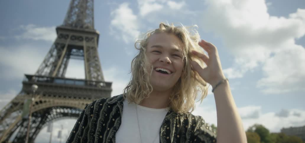 A man smiles and laughs in front of the eiffel tower