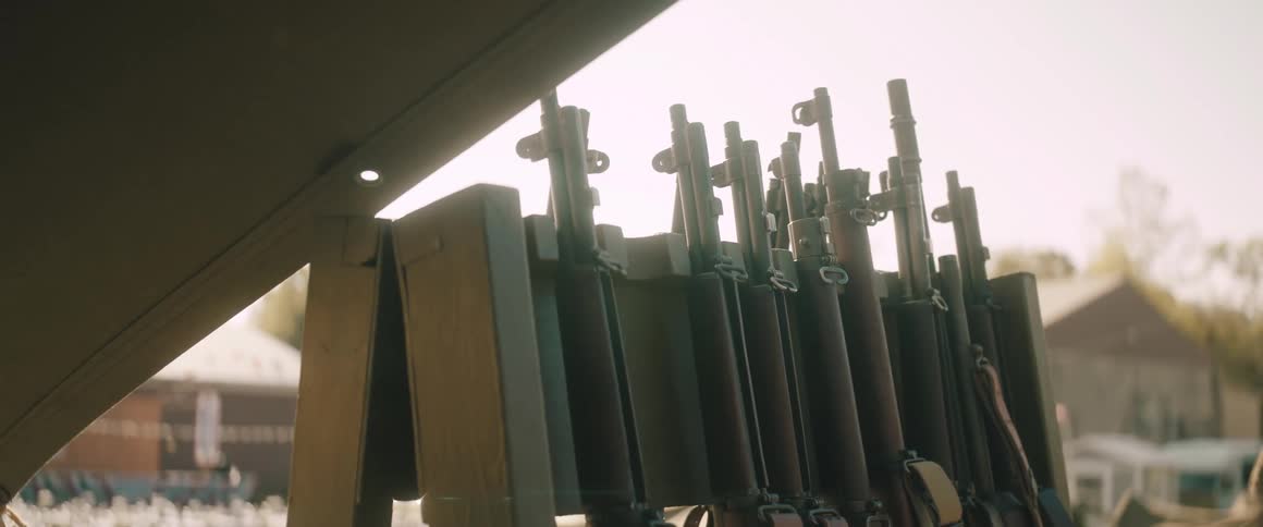 Rifles stand in a frame near a canvas tent in a residential neighborhood on an autumn day