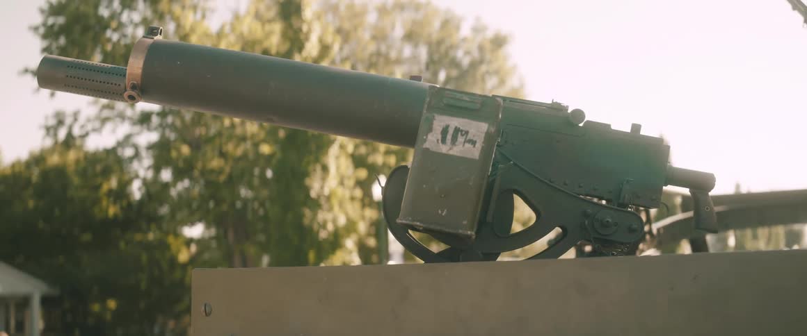 Heavy machine gun mounted on a fixed support positioned outdoors with trees in the background