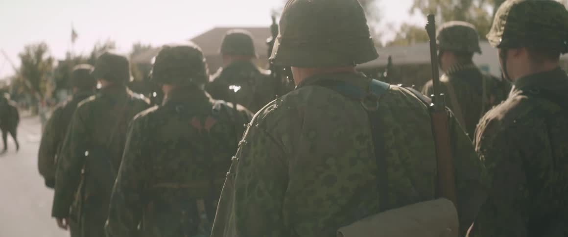 Soldiers wearing their uniforms and carrying firearms march along a road on an autumn day