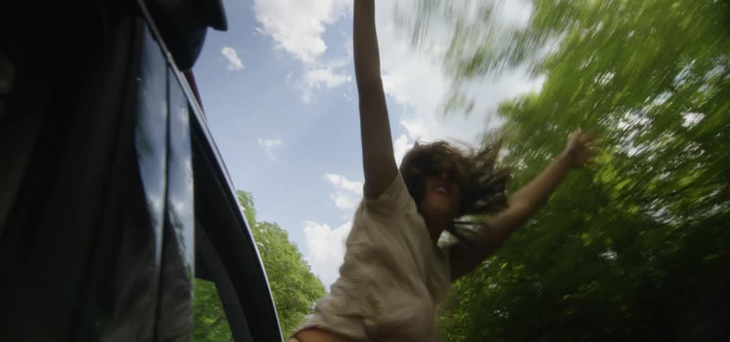 Woman hangs out of a moving vehicle