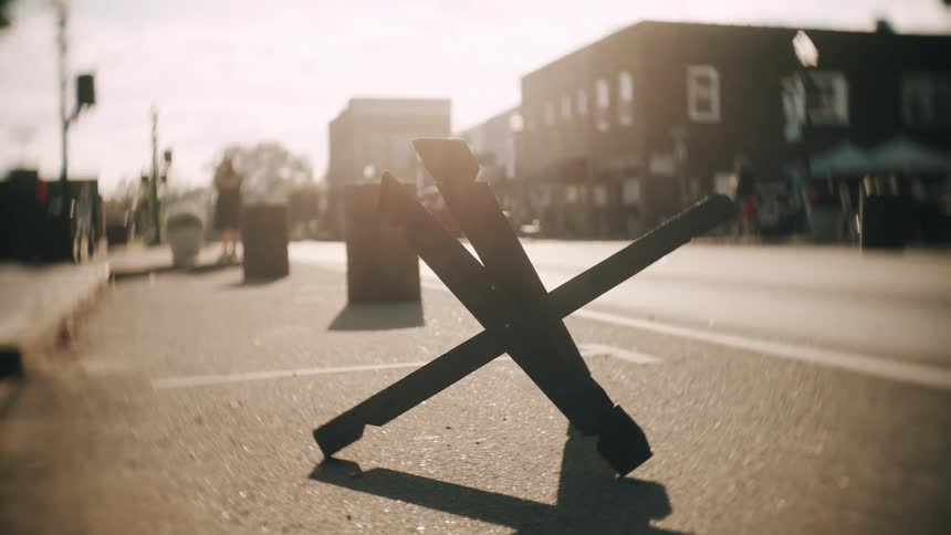 Metal barricade in x shape on street with blurred urban background and soft evening light