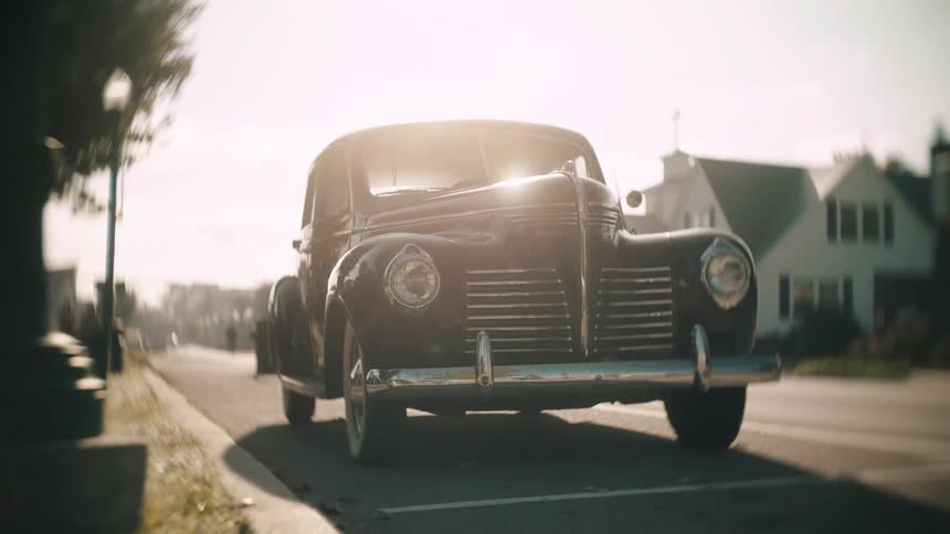 Vintage car parked on a residential street under direct sunlight