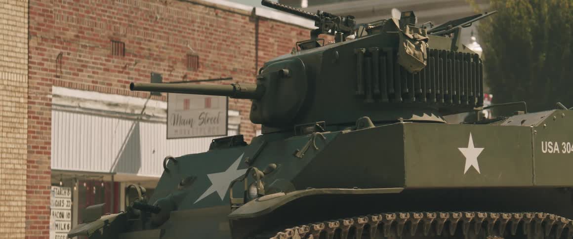 A tank driving down a road in a city